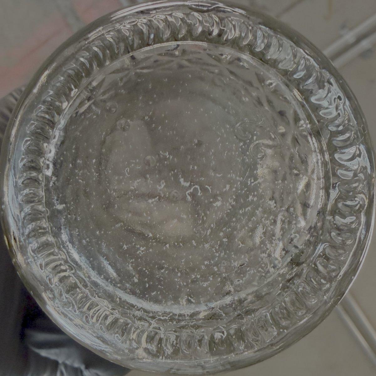 Water from the chewing test seen through the bottom of a jar, full of white specks of retainer plastic